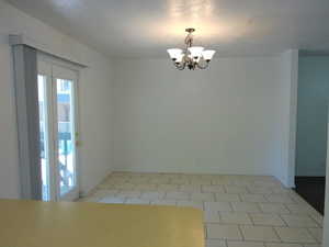Spare room with suspended lighting, a textured ceiling, and light tile patterned floors