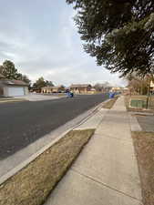 View of asphalt street featuring a residential view and curbs