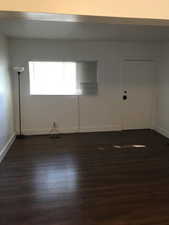 Unfurnished room featuring baseboards and dark wood-style flooring