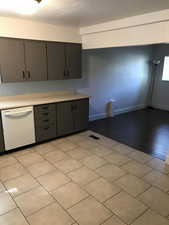 Kitchen featuring white dishwasher, light countertops, gray cabinets, and a textured ceiling