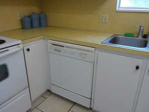 Kitchen featuring white appliances, white cabinetry, light tile patterned floors, and light countertops