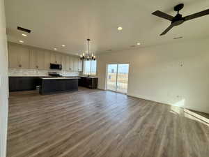 Kitchen featuring open floor plan, a center island, suspended lighting, light countertops, and dark wood-type flooring