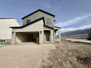 Back of property featuring a mountain view, gravel driveway, and stone siding