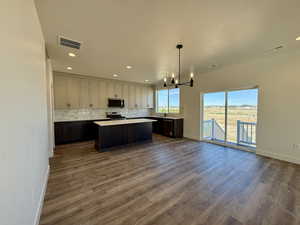 Dual tone kitchen with a kitchen island, open floor plan, hanging lights, light countertops, and dark wood finished floors