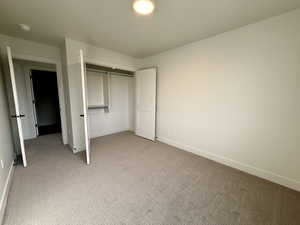 Unfurnished bedroom featuring light carpet and a closet