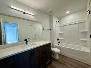 Bathroom with vanity, dark wood-type flooring, and shower / bathtub combination