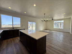Kitchen featuring a kitchen island, dark wood-type flooring, hanging lights, open floor plan, and a textured ceiling