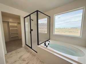 Bathroom featuring a walk in closet, a bath, a stall shower, a mountain view, and light marble finish flooring