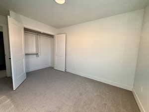 Unfurnished bedroom featuring light colored carpet and a closet