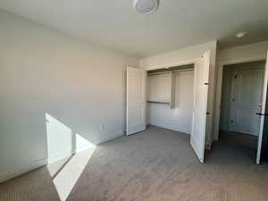 Unfurnished bedroom featuring a closet and light carpet