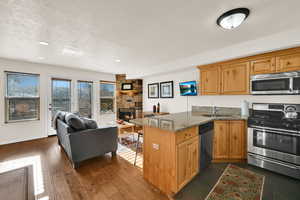 Kitchen featuring stainless steel appliances, dark stone countertops, a peninsula, a breakfast bar area, and a textured ceiling
