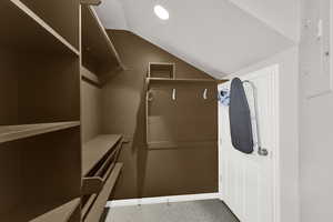 Walk in closet with light colored carpet and lofted ceiling