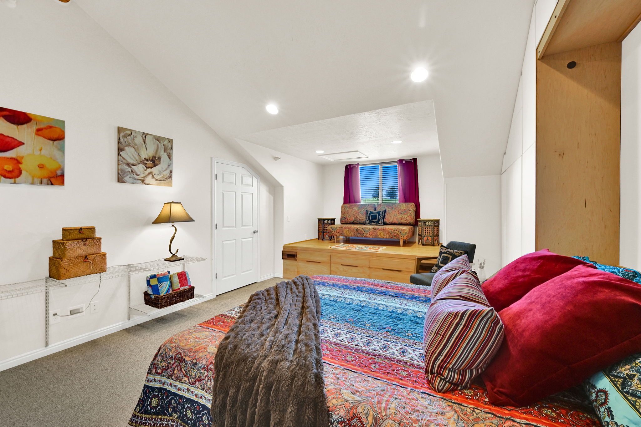 Spacious room featuring sloped ceilings, recessed lighting, and soft carpet flooring