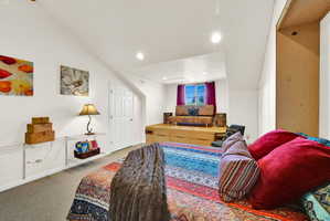 Spacious room featuring sloped ceilings, recessed lighting, and soft carpet flooring