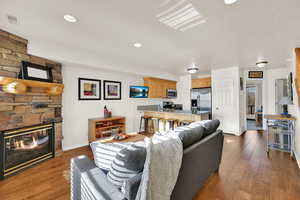 Living room featuring dark wood-style floors, a stone fireplace, and recessed lighting