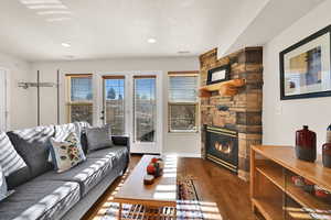 Living area featuring plenty of natural light, a stone fireplace, dark wood-style flooring, and recessed lighting