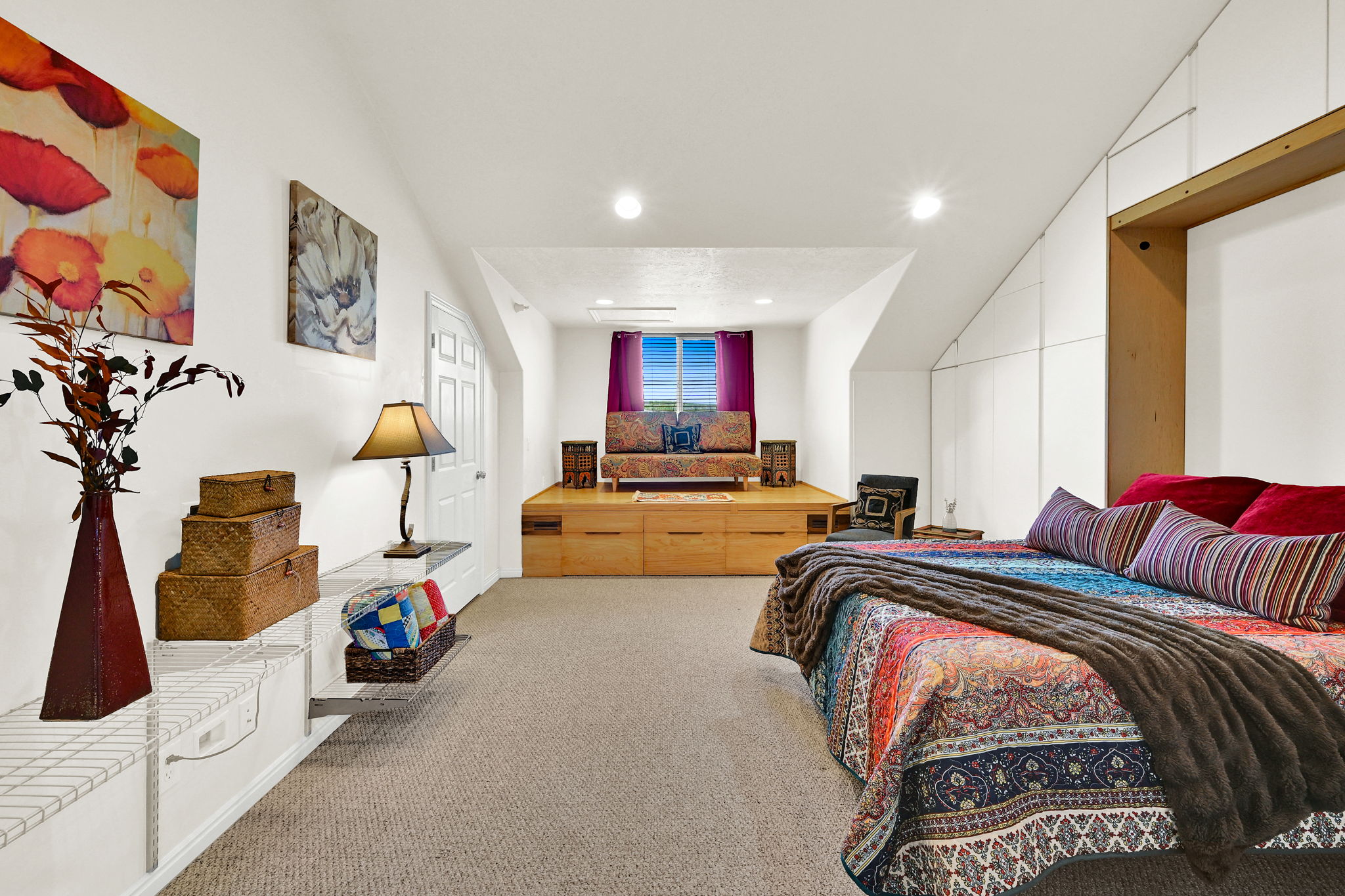 Versatile room featuring an elevated platform with integrated storage, sloped ceilings, recessed lighting, and soft carpet flooring