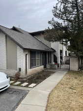 View of front of property with a gate, a shingled roof, and brick siding