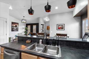 Kitchen with dark countertops, dishwasher, pendant lighting, open floor plan, and vaulted ceiling