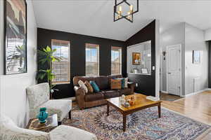 Living area featuring wood finished floors, lofted ceiling, and a chandelier