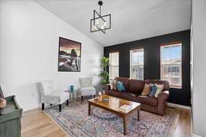 Living area with lofted ceiling, light wood finished floors, and suspended lighting