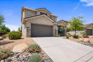 View of front of home with stone siding, concrete driveway, stucco siding, and a garage