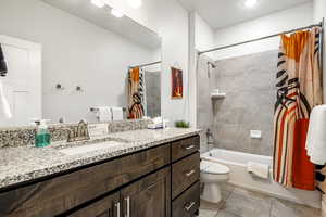 Bathroom featuring vanity, shower / bathtub combination with curtain, and light tile patterned floors
