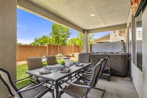 Fenced backyard with a hot tub, outdoor dining space, and a patio