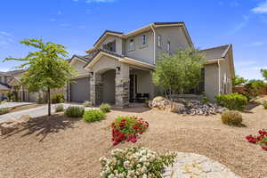 View of front facade with stucco siding, concrete driveway, a tile roof, and stone siding