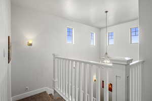 Hallway featuring a chandelier and an upstairs landing