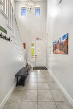 Foyer entrance featuring light tile patterned flooring, a chandelier, and a high ceiling