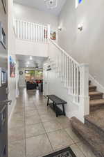 Foyer entrance featuring light tile patterned flooring, a high ceiling, and a ceiling fan