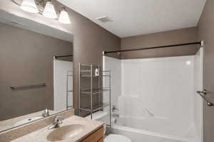Full bathroom with vanity, bathtub / shower combination, and a textured ceiling
