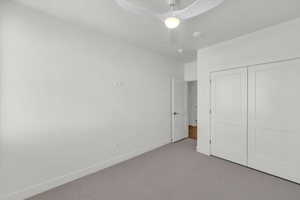 Unfurnished bedroom featuring carpet flooring, a closet, and a ceiling fan