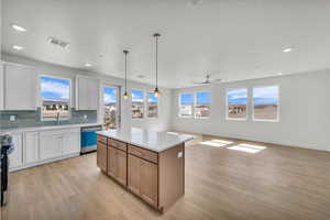 Dual tone kitchen featuring dual tone cabinetry, open floor plan, a kitchen island, hanging light fixtures, and light wood-style flooring