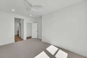 Unfurnished bedroom featuring carpet, a ceiling fan, recessed lighting, and ensuite bath