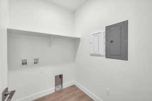 Laundry area featuring electric panel, hookup for a washing machine, and light wood-style flooring