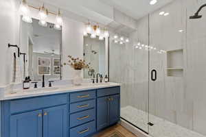 Full bath with a shower stall, double vanity, and ceiling fan