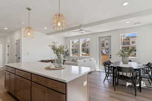 Kitchen featuring hanging light fixtures, a ceiling fan, a center island, and light wood finished floors