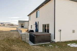 Rear view of house with a lawn, a patio area, and a hot tub