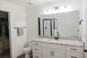 Full bathroom with a shower stall, vanity, and a spacious closet