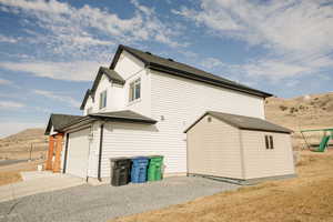 View of property exterior with concrete driveway, a shingled roof, and a mountain view