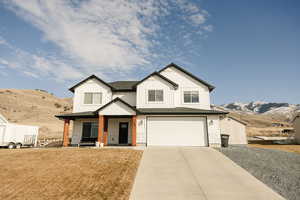 Modern farmhouse with a mountain view, board and batten siding, a porch, and an attached garage