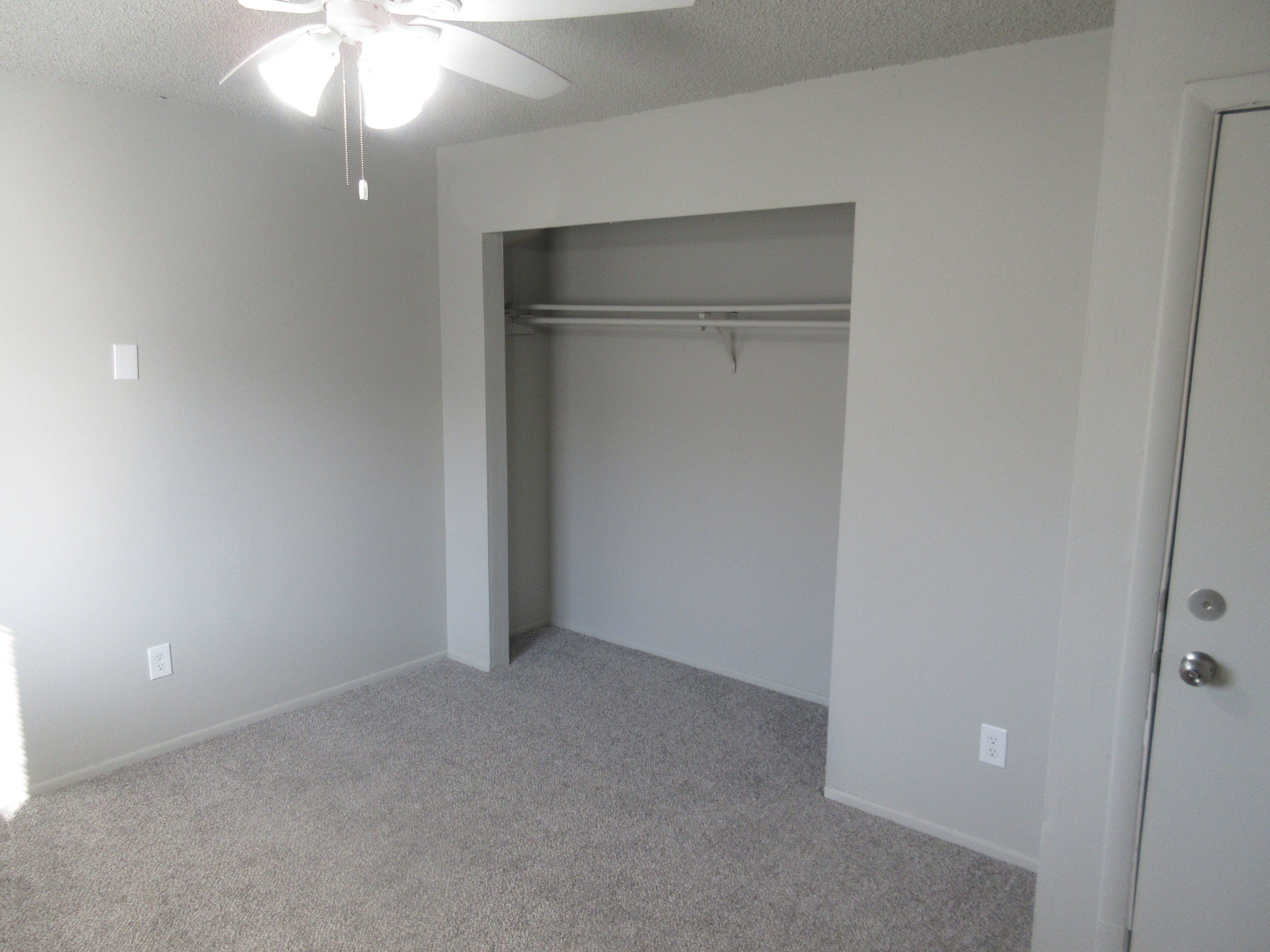 Unfurnished bedroom featuring light colored carpet, a textured ceiling, a ceiling fan, and a closet