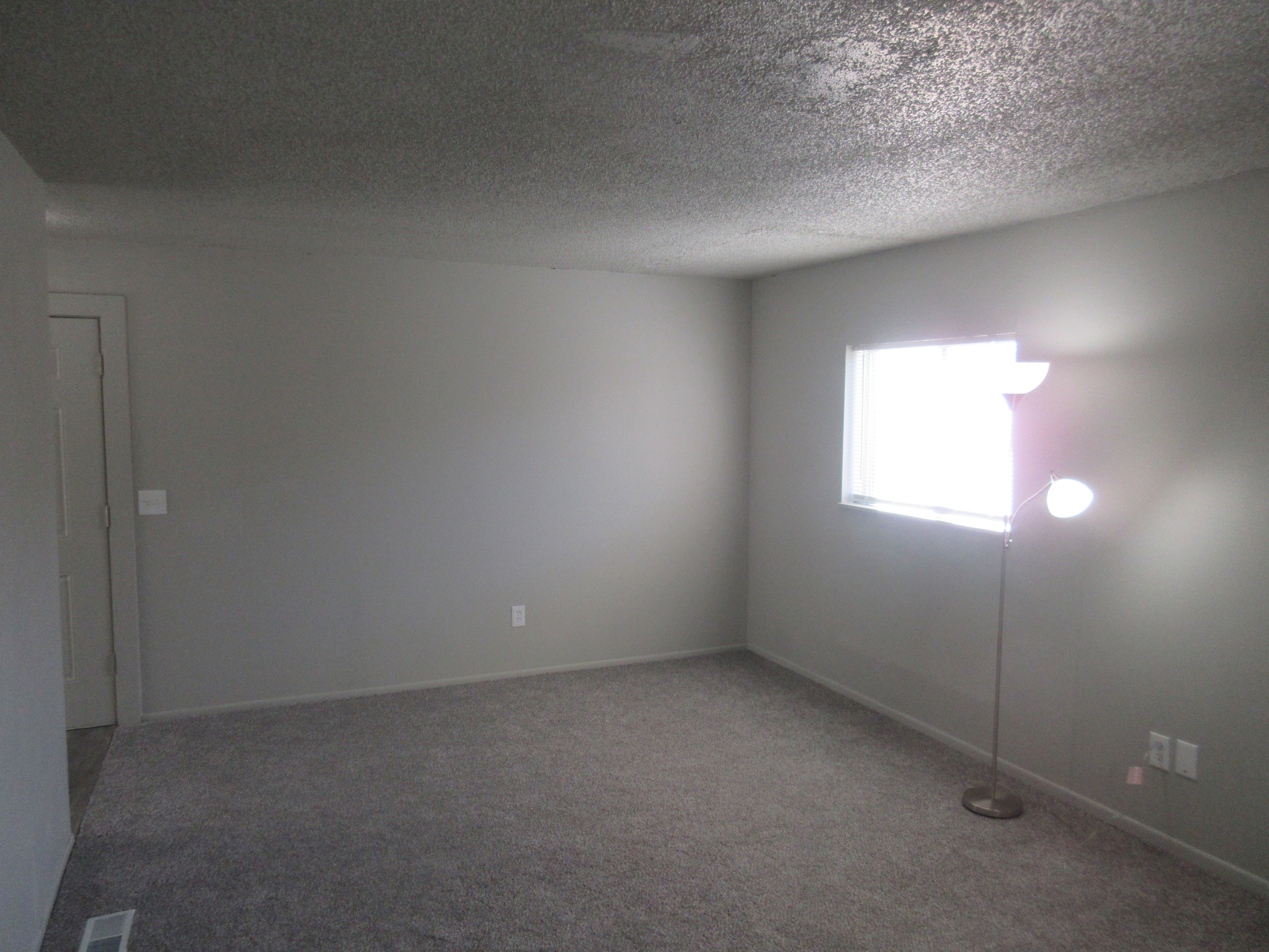 Carpeted spare room with a textured ceiling and baseboards