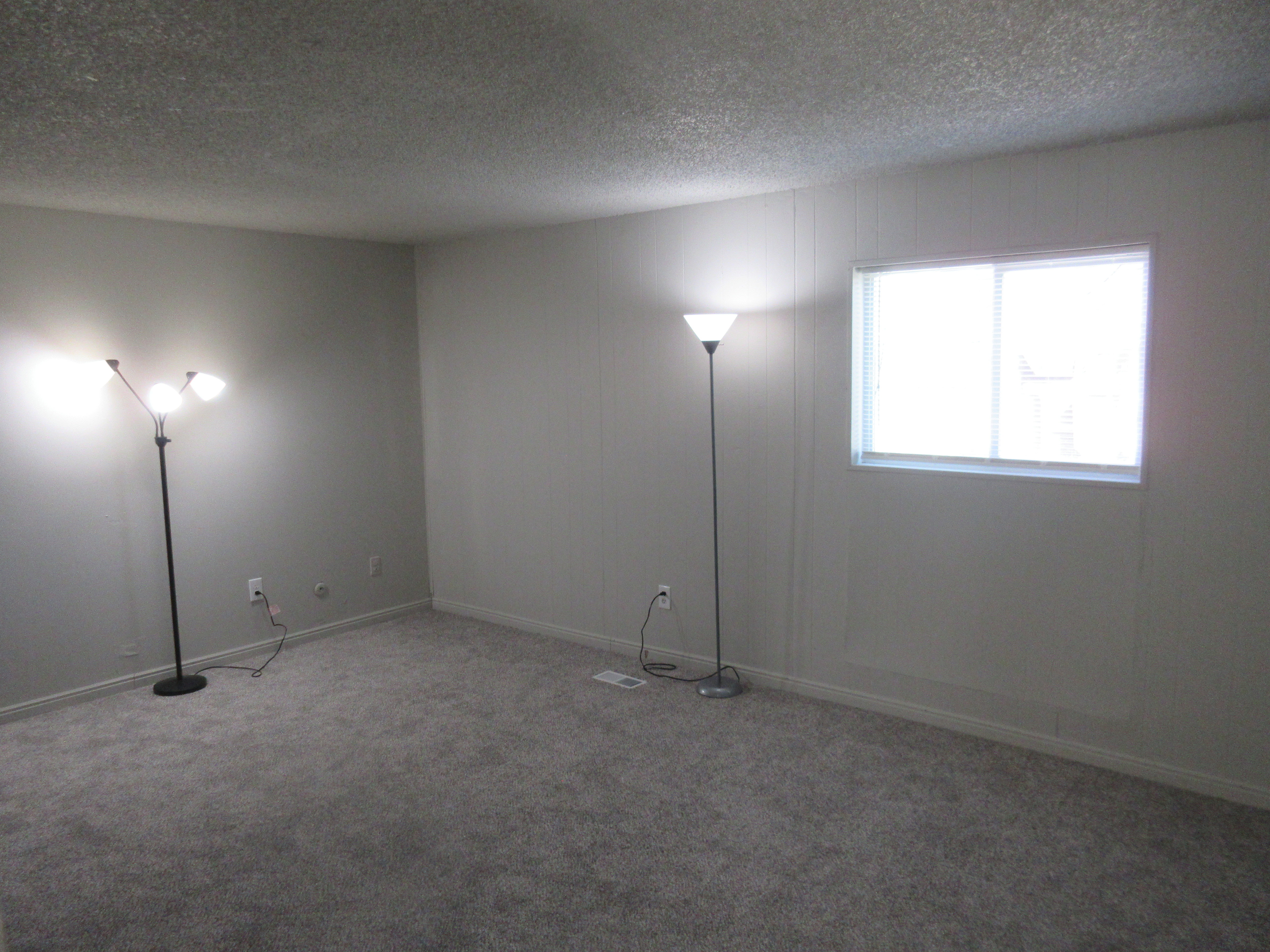 Carpeted empty room with a textured ceiling and baseboards