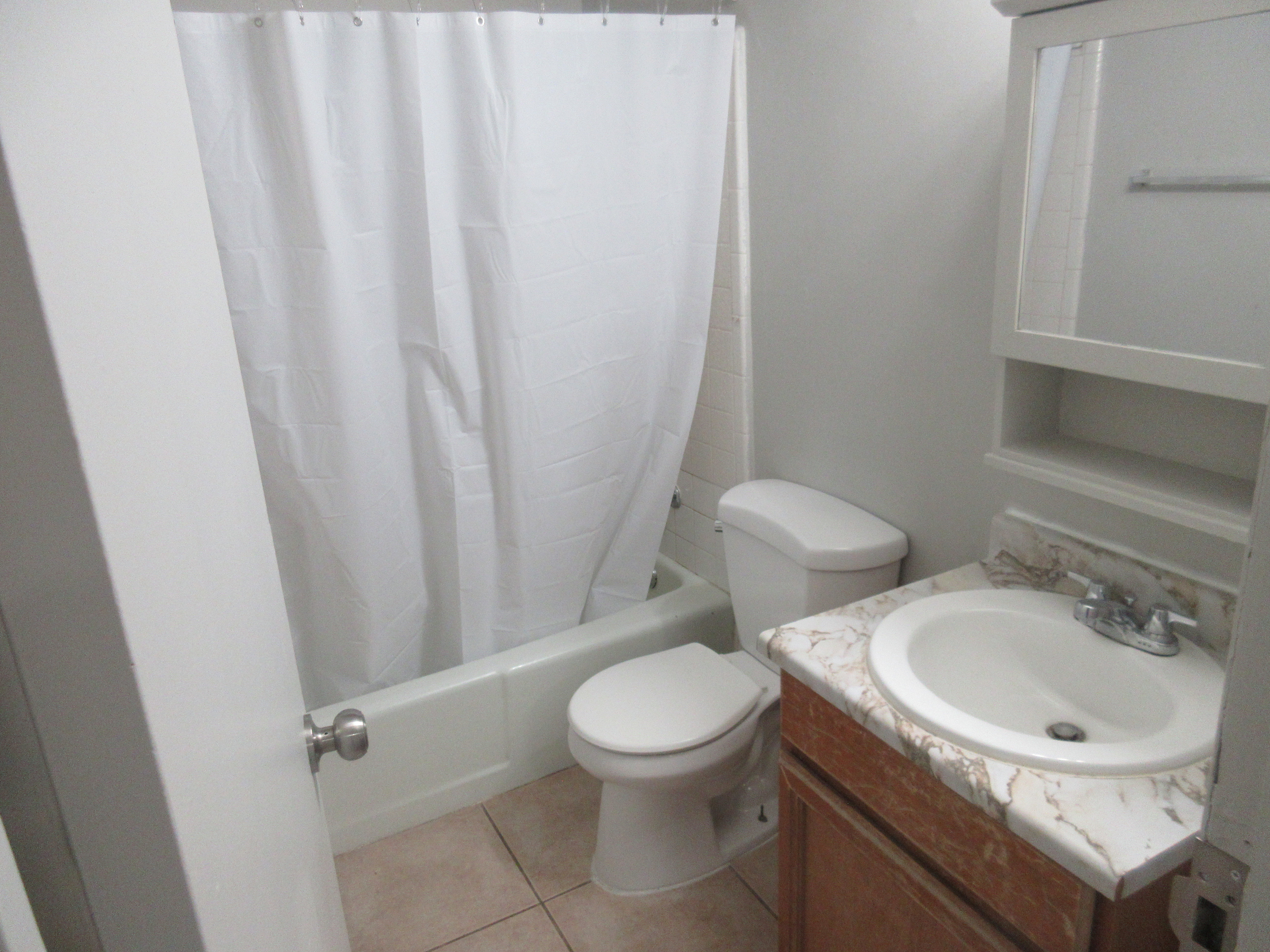Full bath with vanity, shower / bath combo, and light tile patterned floors