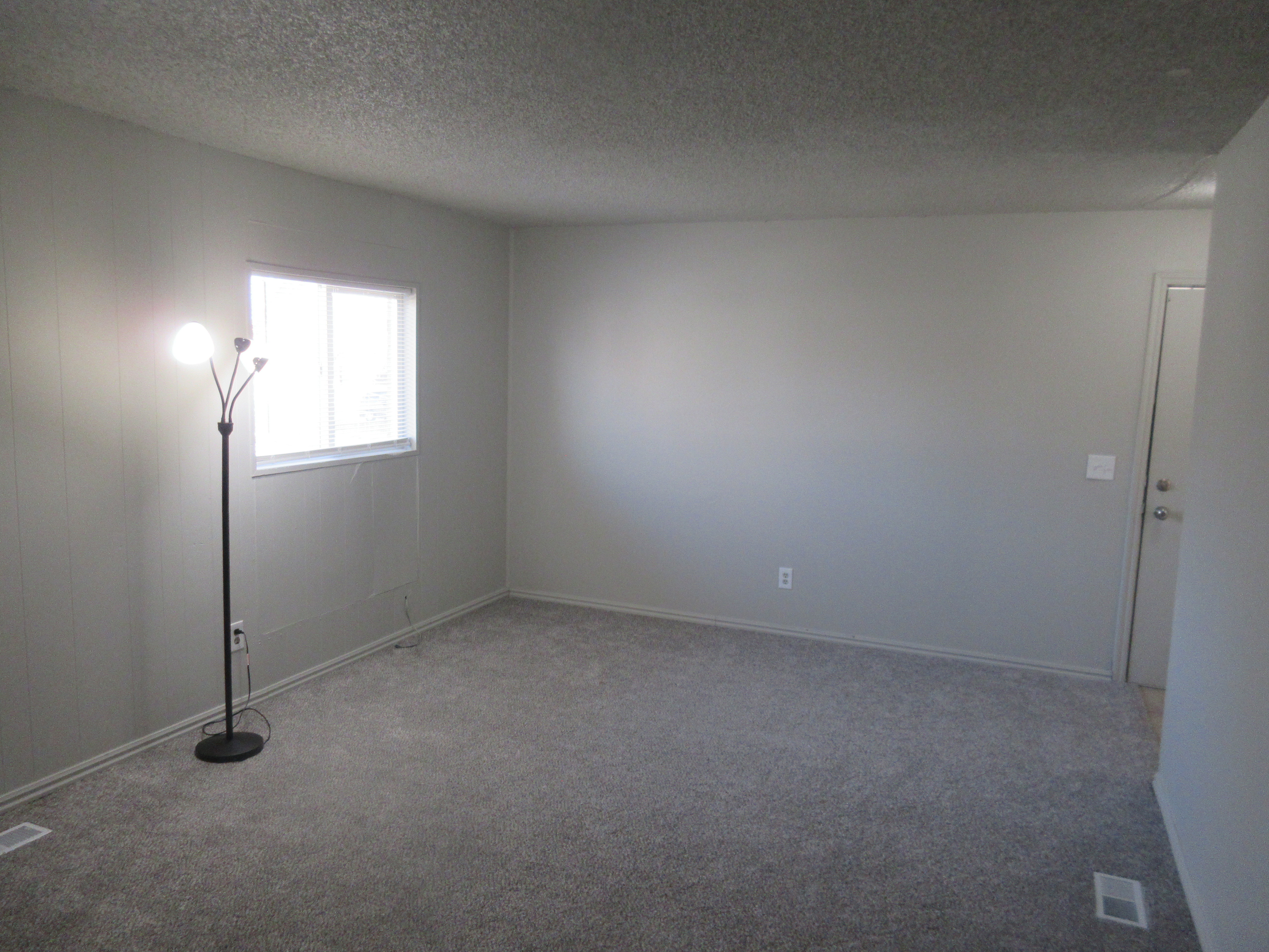 Carpeted empty room with a textured ceiling and baseboards