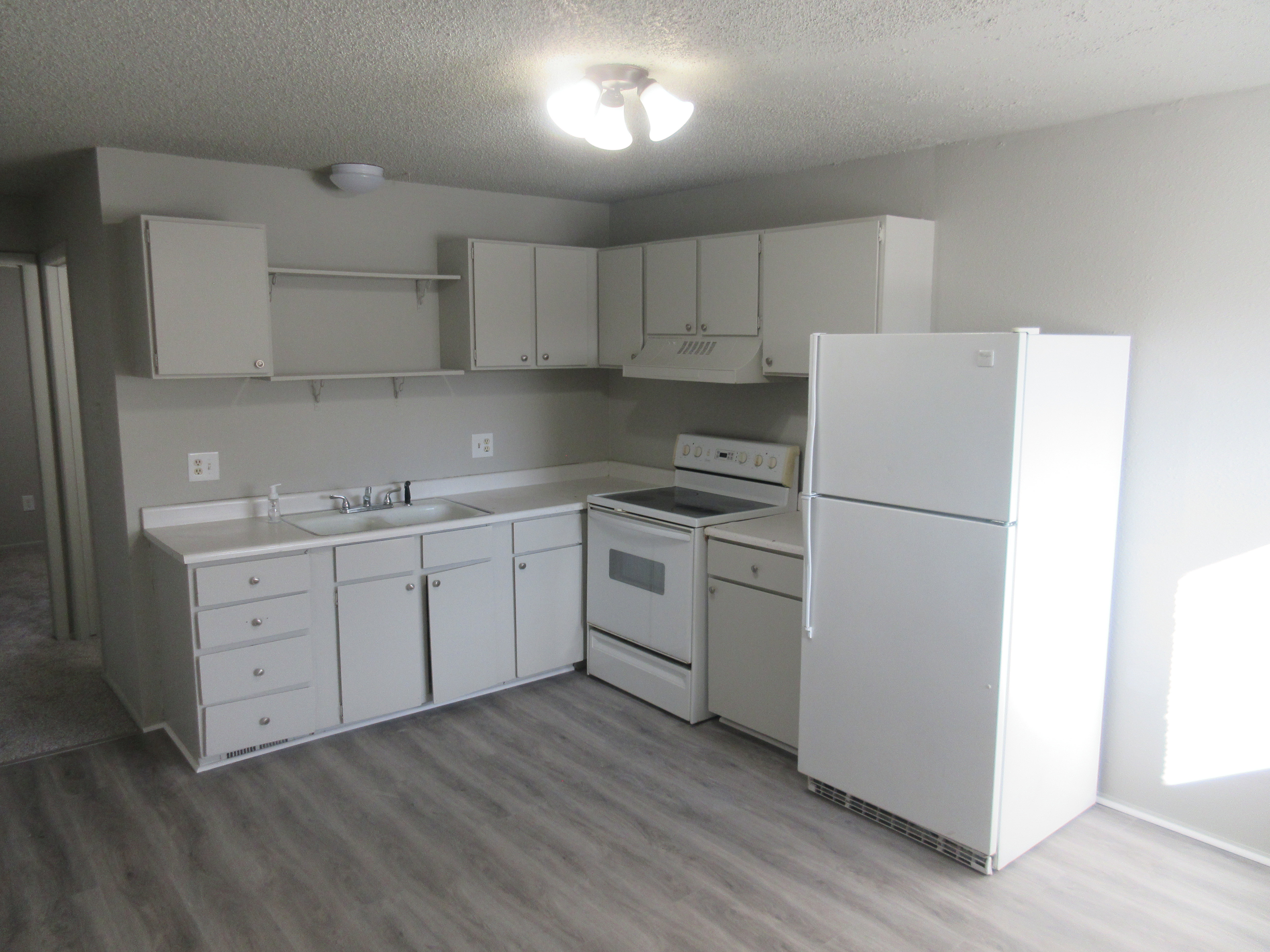 Kitchen featuring white appliances, white cabinetry, open shelves, light countertops, and a textured ceiling