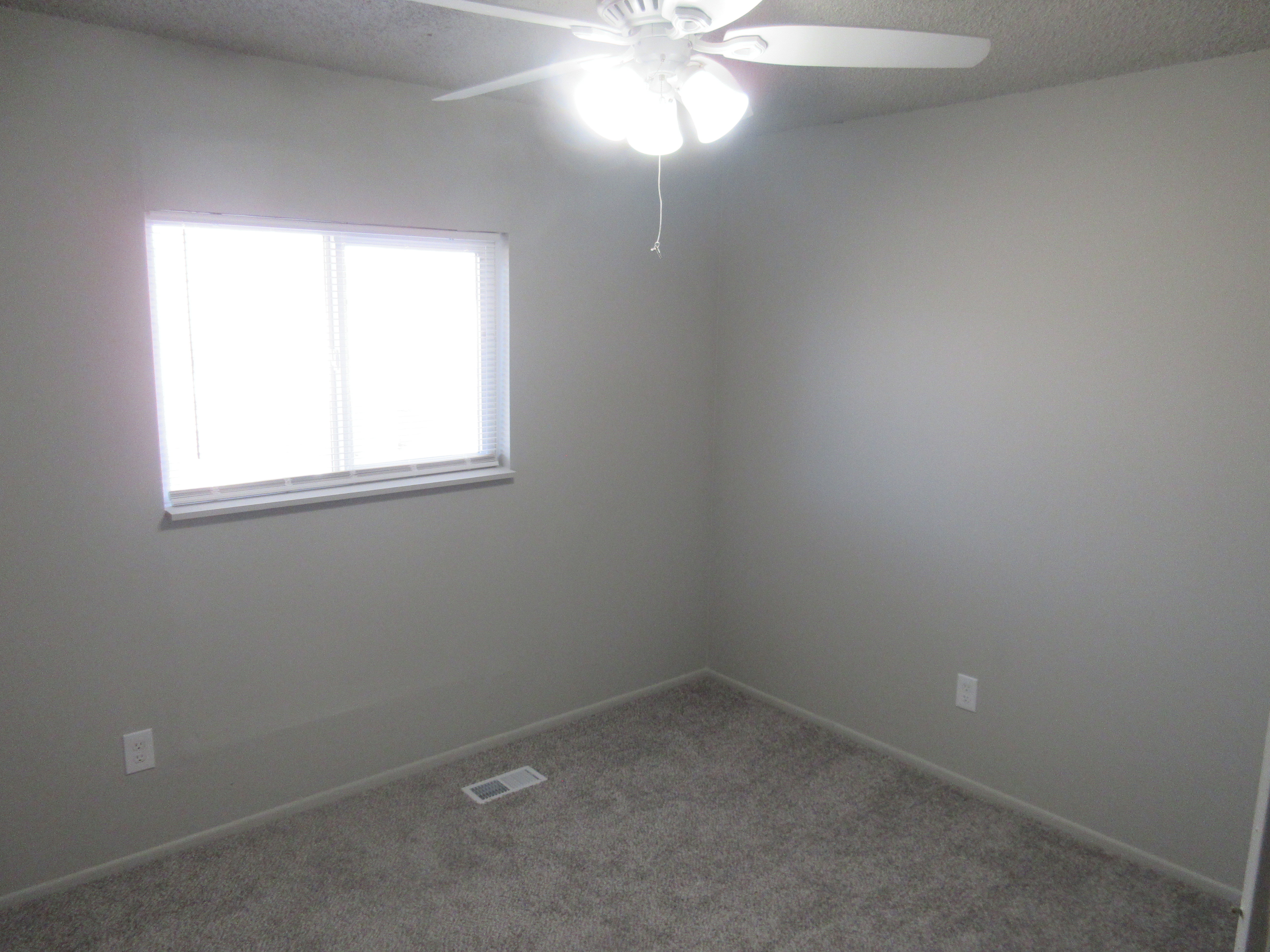 Carpeted empty room with ceiling fan and a textured ceiling